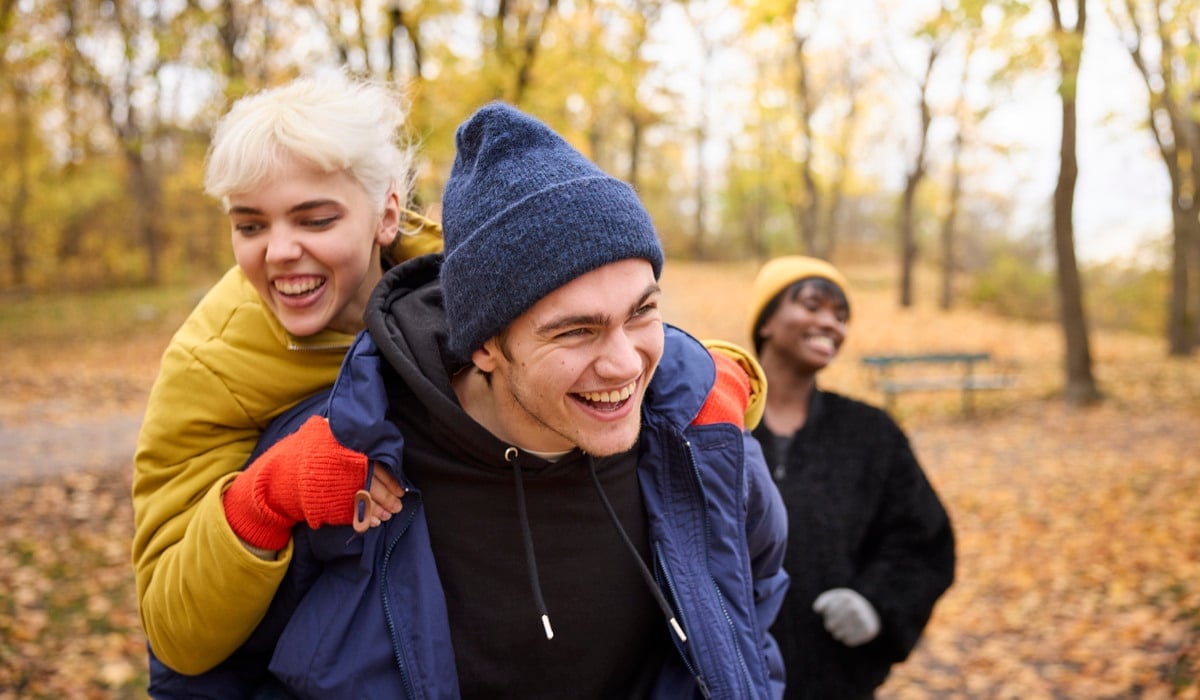 En man som bär en kvinna på ryggen i en park.